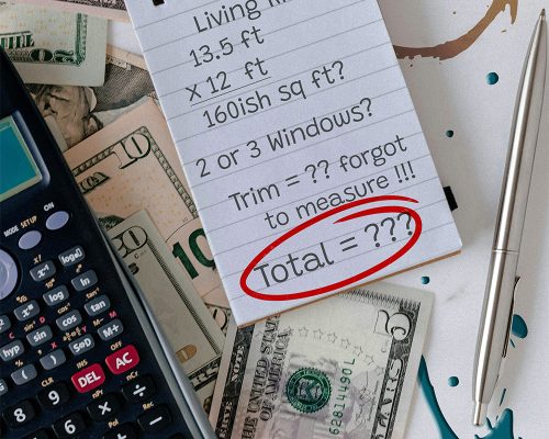Notepad with half finished calculations next to a calculator and a pile of money on a dirty table